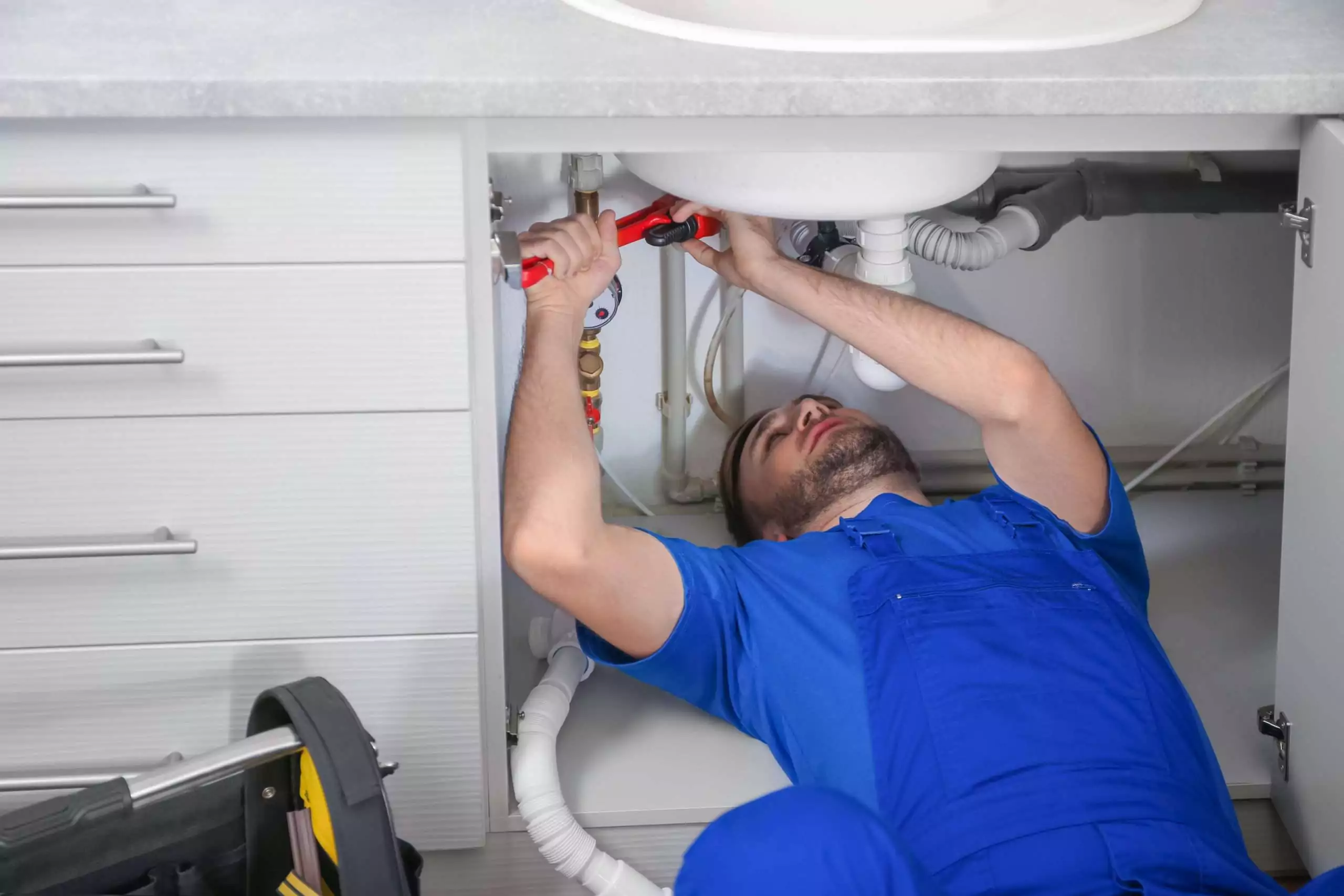 Man Repairing Sink Under Cabinet in Home