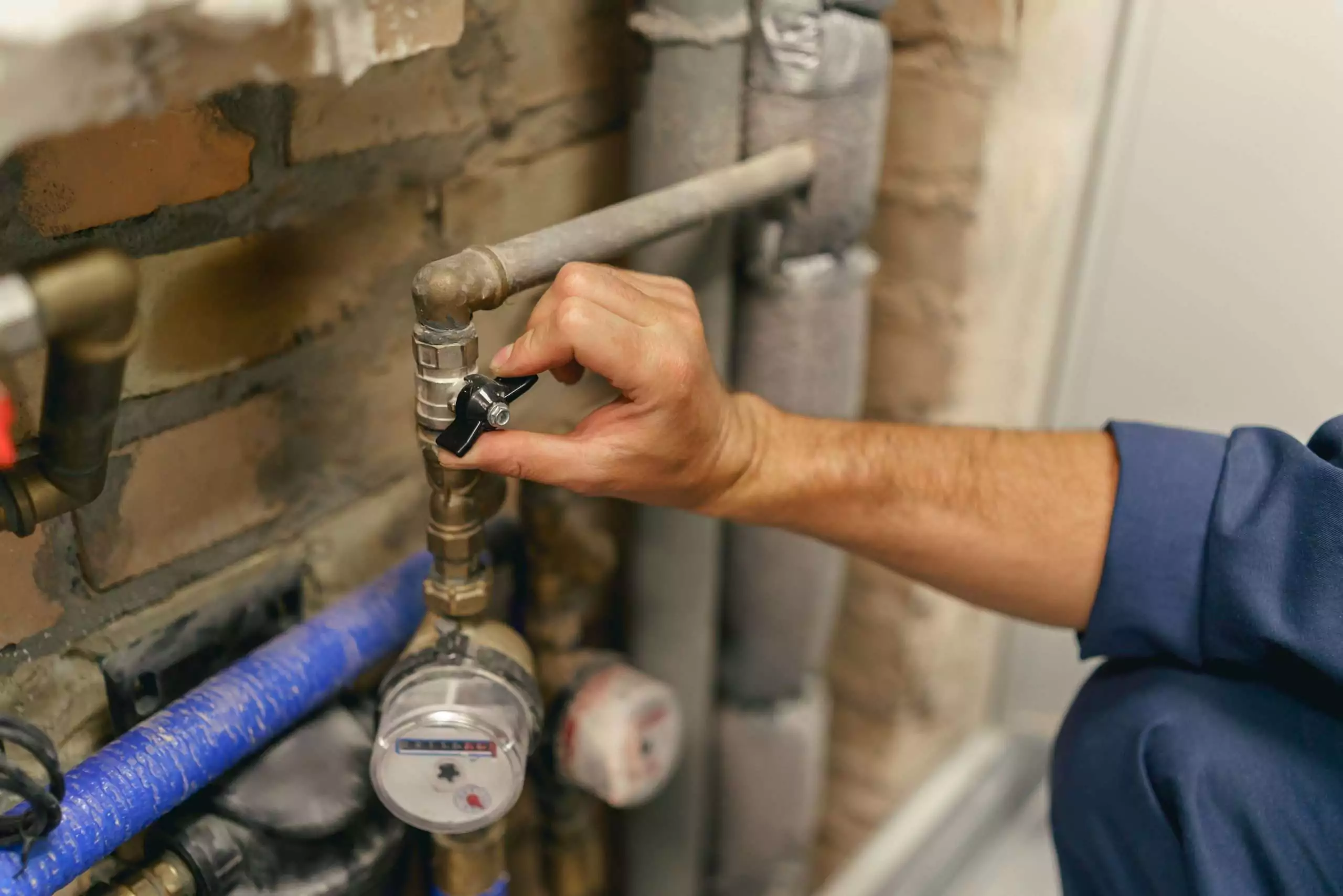Plumber hand is going to turn off the valve of water pipe before repairing