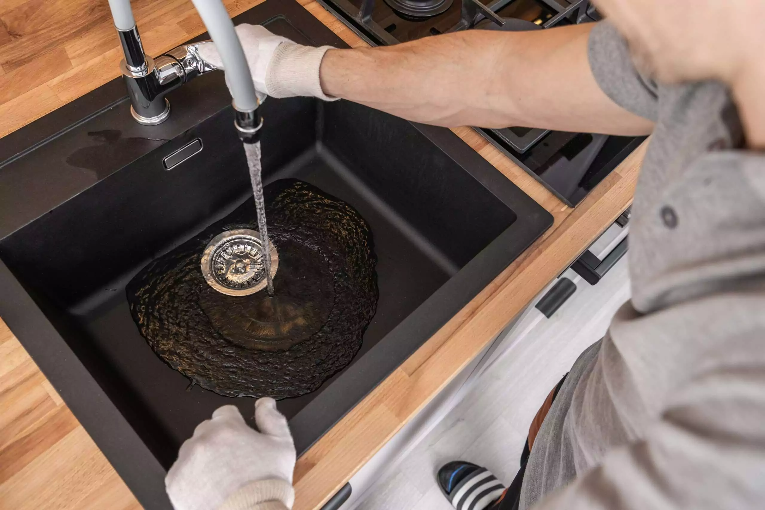 Adult Cleaning a Black Kitchen Sink with Water