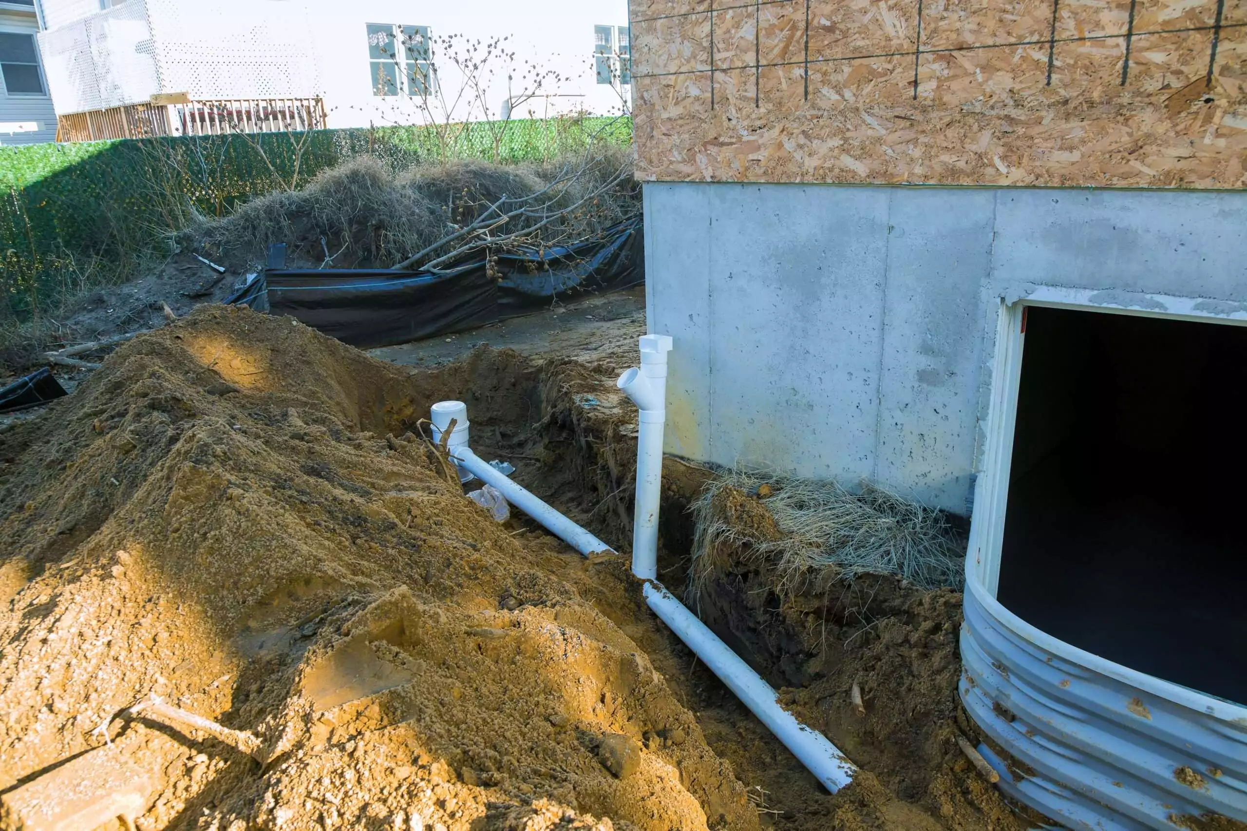 Foundation Drainage Construction with White Pipes and Dirt