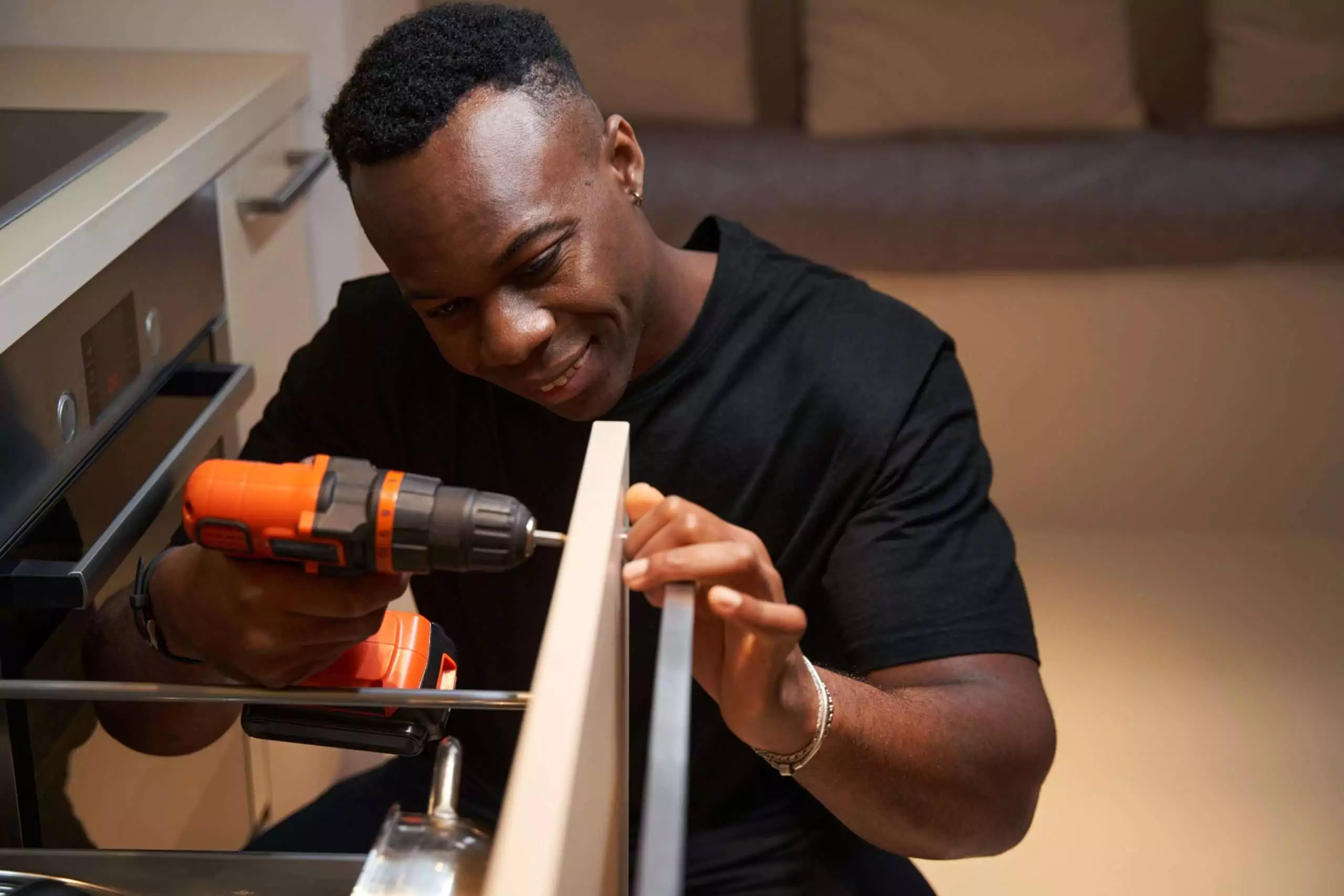 Man Assembling Cabinet with Drill in Kitchen