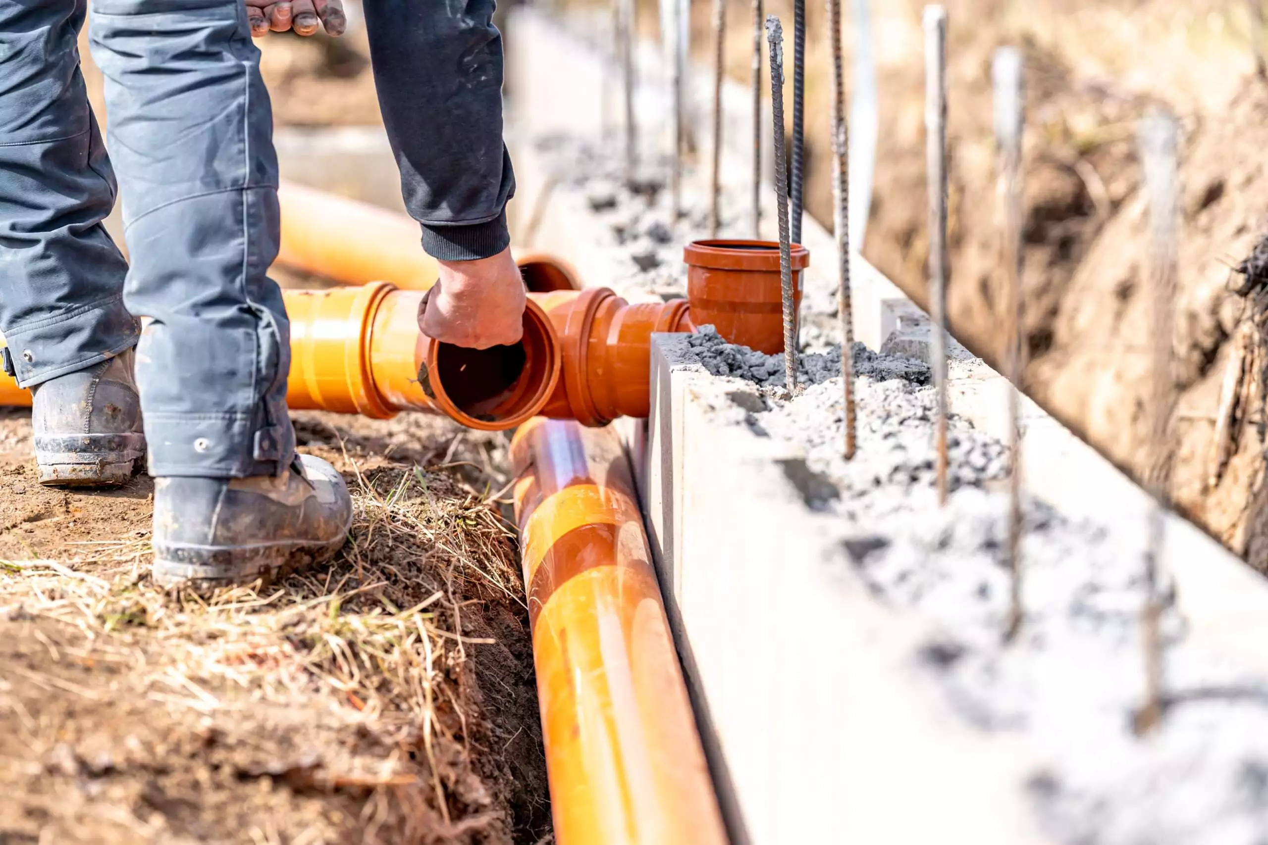 Worker Connecting Drainage Pipes at a Construction Site