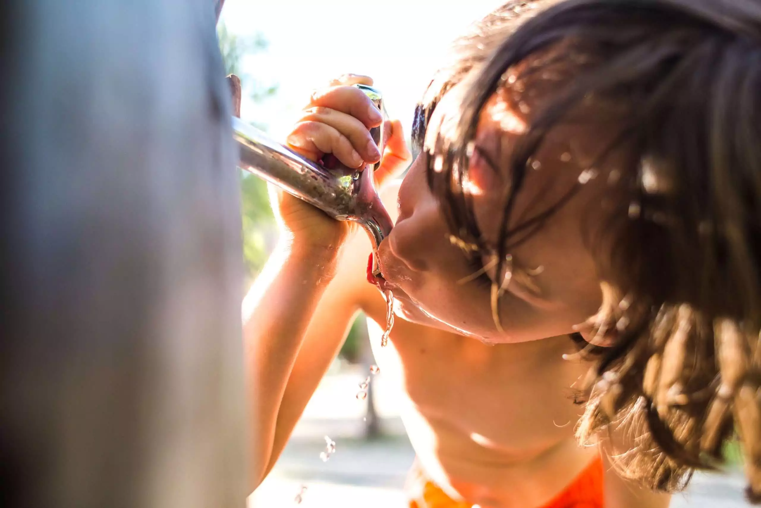 Thirsty Child Drinks from Outdoor Water Fountain
