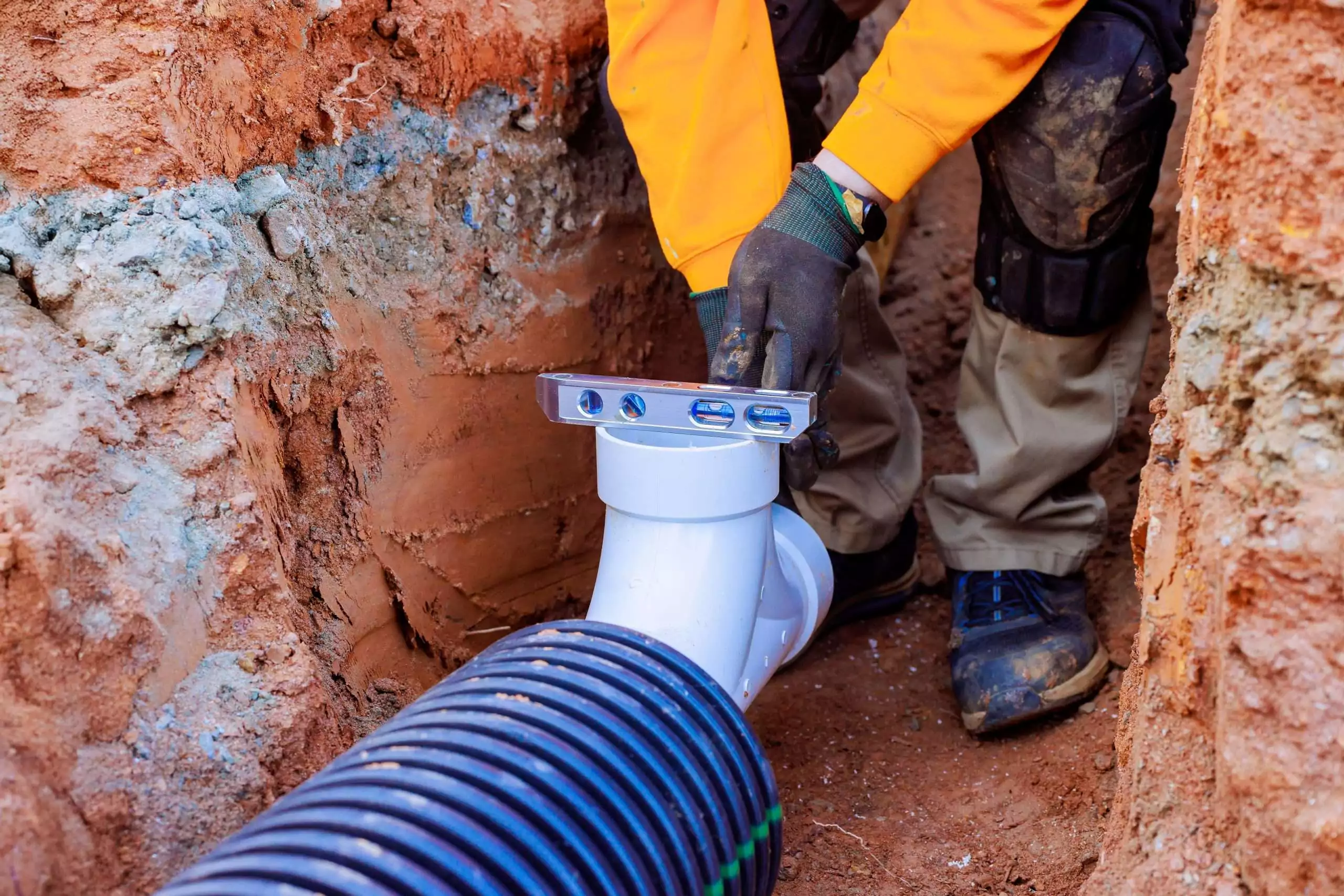 Worker installs drainage system with precision tools in construction site during works day